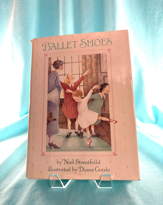 Book titled 'Ballet Shoes' with illustration of children dancing on a light blue background