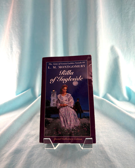 Book titled 'Rilla of Ingleside' by L. M. Montgomery on a stand against a light curtain background