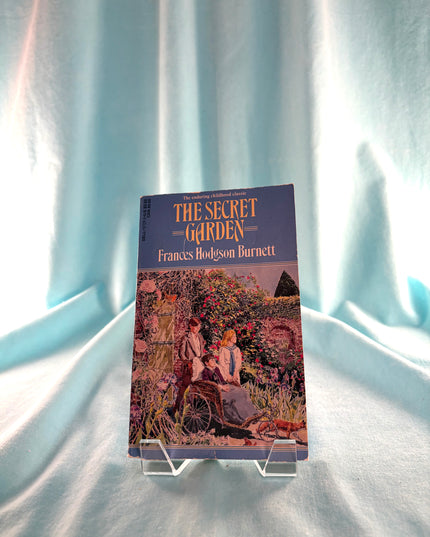Book titled 'The Secret Garden' by Frances Hodgson Burnett on a light blue fabric background