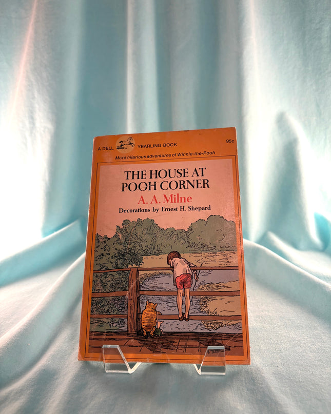 Book titled 'The House at Pooh Corner' by A. A. Milne on a stand against a light background