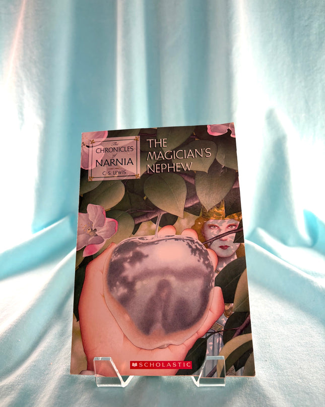 Book cover of 'The Magician's Nephew' from The Chronicles of Narnia on a light blue fabric background