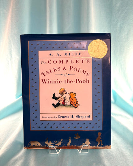 Book titled 'The Complete Tales & Poems of Winnie-the-Pooh' on a light blue background
