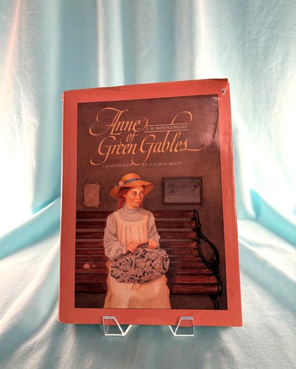 Book cover of 'Anne of Green Gables' with a character on a stand against a light curtain background