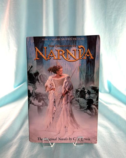 Book titled 'The Chronicles of Narnia' on a stand with a white curtain background