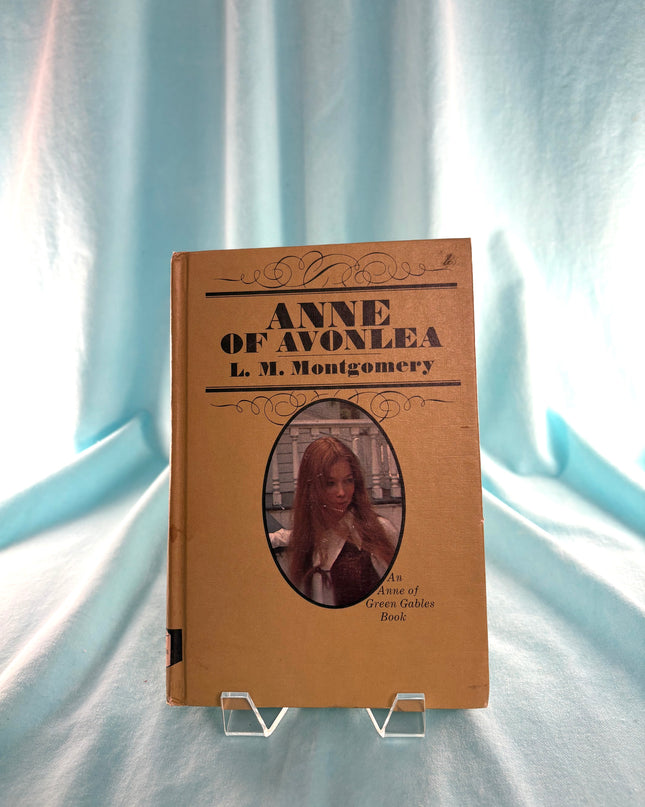 Book titled 'Anne of Avonlea' by L.M. Montgomery on a light blue fabric background