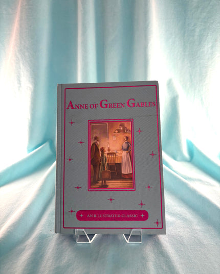 Book titled 'Anne of Green Gables' on a stand with a light blue curtain background