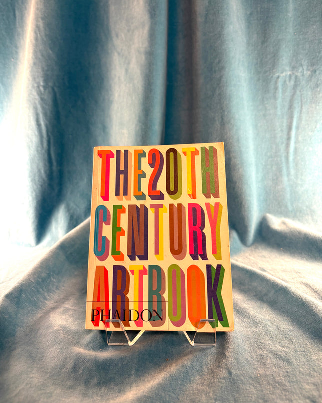Colorful book titled 'The 20th Century Artbook' by Phaidon on a gray fabric background