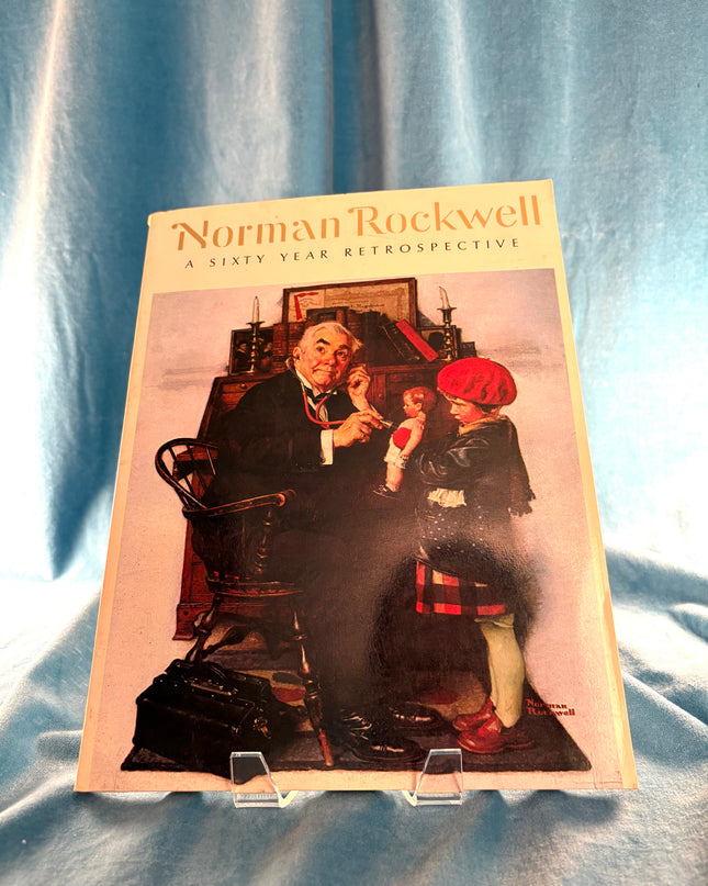 Booklet titled 'Norman Rockwell: A Sixty-Year Retrospective' on a textured blue background
