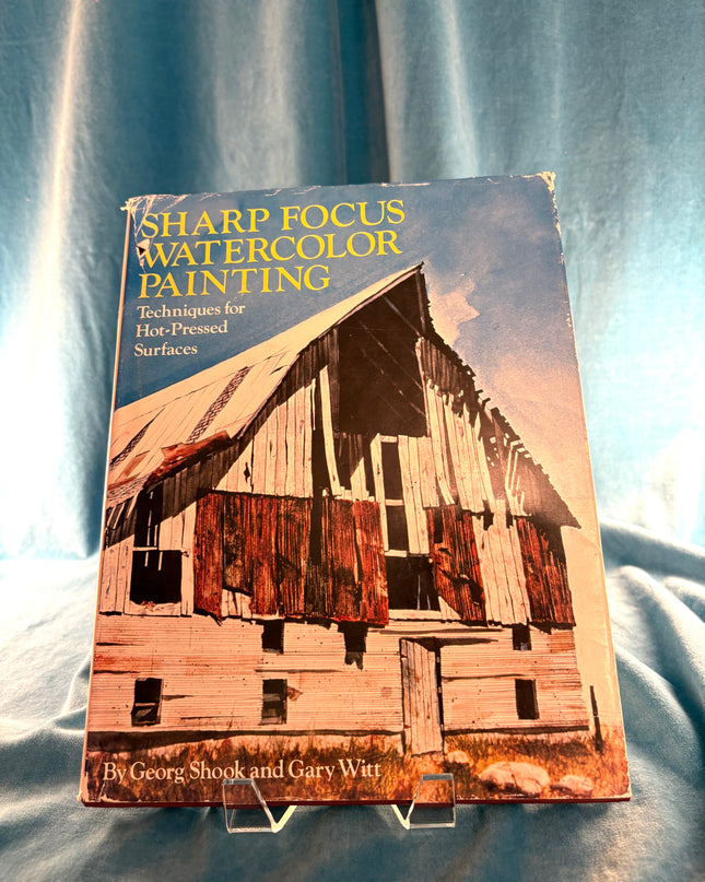 Book titled 'Sharp Focus Watercolor Painting' on a textured fabric background