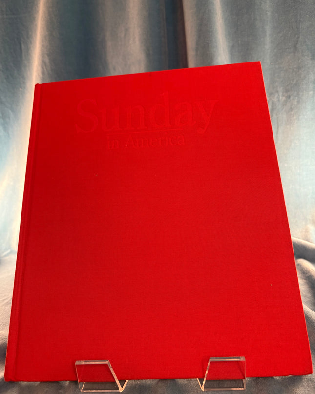 Red book titled 'Sunday in America' on a stand against a gray background