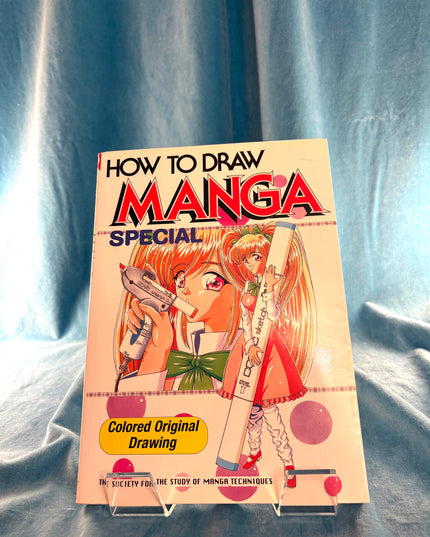 Book titled 'How to Draw Manga Special' on a blue fabric background