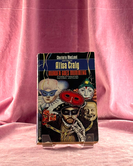 Book titled 'Murder Goes Mumming' by Alisa Craig on a pink fabric background