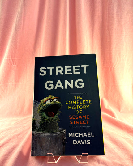 Book titled 'Street Gang: The Complete History of Sesame Street' by Michael Davis on a pink background