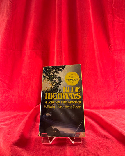 Book titled 'Blue Highways: A Journey into America' by William Least Heat Moon on a red background