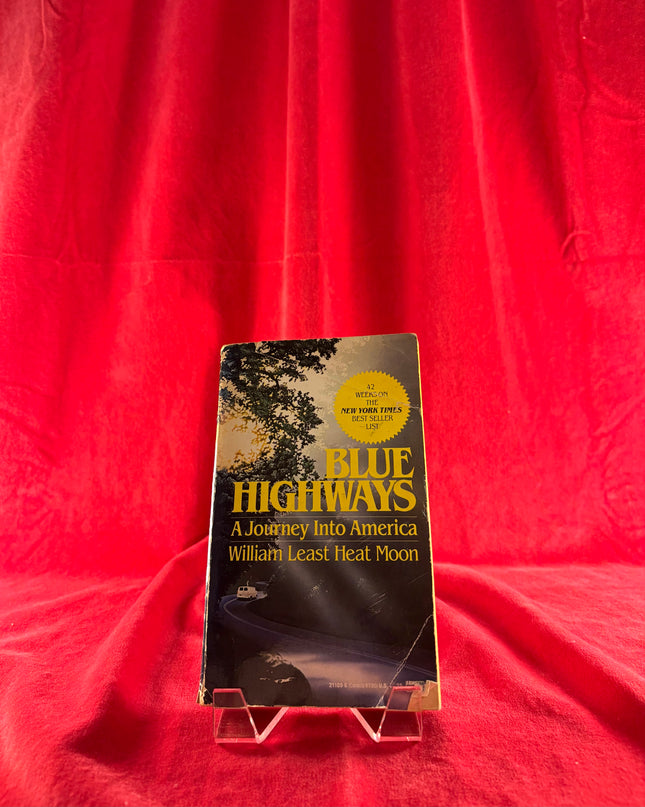 Book titled 'Blue Highways: A Journey into America' by William Least Heat Moon on a red background